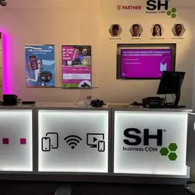 Modernes Telekommunikationsgeschäft mit leuchtendem Tresen, Smartphones und Werbeplakaten.