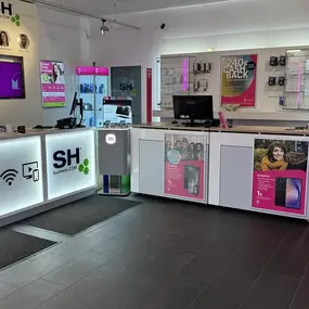 Moderner Telekom Shop mit Beratungsbereich, Smartphones, Zubehör und Werbeplakaten.