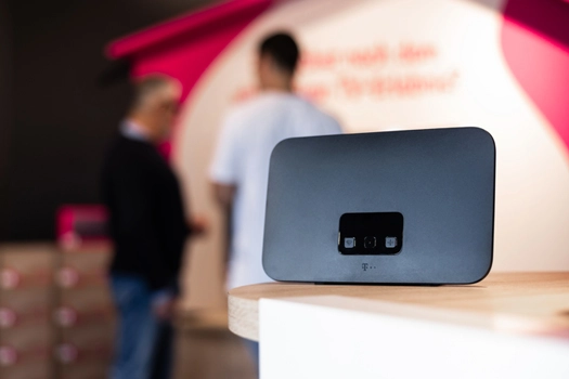 Telekom WLAN-Router auf Tisch, Hintergrund mit unscharfen Personen im Laden